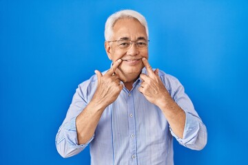 Sticker - Hispanic senior man wearing glasses smiling with open mouth, fingers pointing and forcing cheerful smile