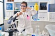 © Krakenimages.com - Hispanic girl with down syndrome working at scientist laboratory smiling doing talking on the telephone gesture and pointing to you. call me.