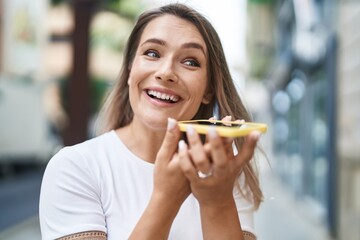 Wall Mural - Young caucasian woman smiling confident talking on the smartphone at street