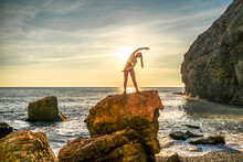 Girl Gymnast Is Training On The Beach By The Sea Sunset. Does Twine. Photo Series.
