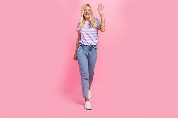 Poster - Full length portrait of cheerful lovely person toothy smile arm palm waving walking isolated on pink color background