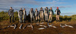 © Mat Hayward - Group of 9 fishermen made up of men and women holding large salmon on a river bank. More fish spell our the word Alaska on the tundra
