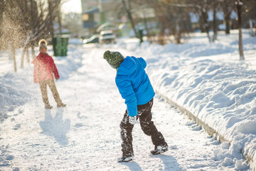 Children playing in the snow-covered road in the snow. Boy in bl