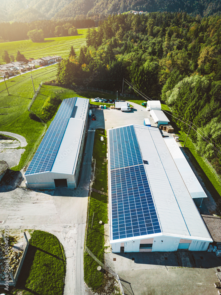 Vertical photo of two industrial buildings with a roof covered in solar ...