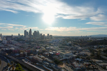 aerial shot of the skyscrapers and office buildings in the city skyline over Los Angeles State Historic Park with lush green trees with blue sky and clouds at sunset in Los Angeles California