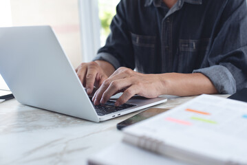 Canvas Print - Man sitting at table, working on laptop computer at home office with document on table, work planning