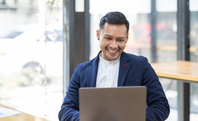 Young business Asian man working at workplace with laptop and papers on desk