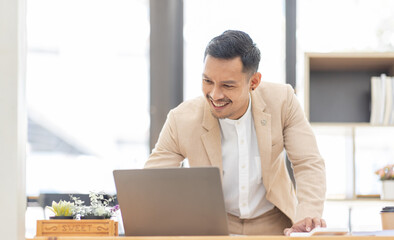 Wall Mural - Young business Asian man working at workplace with laptop and papers on desk