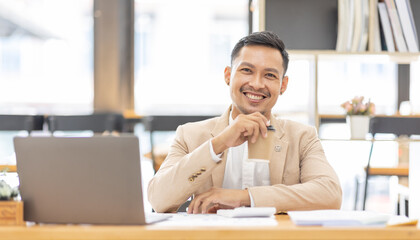 Wall Mural - Young business Asian man working at workplace with laptop and papers on desk