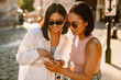 © Drobot Dean - Two young beautiful smiling stylish asian girls looking at phone