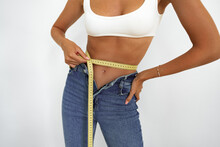 Close Up Shot Of Fit Woman With Slim Body Measuring Her Waistline On White Background