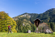 Germany, Bavaria, Female Hiker Walking Toward Wayside Shrine In Chiemgau Alps