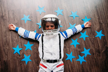 Happy Girl Wearing Space Costume Lying On Floor With Blue Stars At Home