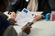 © Mediaphotos - Close up of unrecognizable consulate worker handing approved visa application form to black man in office