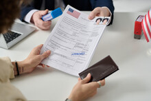 Close Up Of Woman Getting US Visa In Immigration Office And Holding Approved Forms