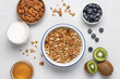 © Anna Puzatykh - Oatmeal granola, milk, berries and fruits on light background. Ingredients for making homemade breakfast top view