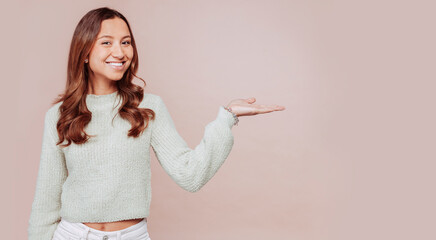 Horizontal banner of smiling young multiracial woman with curly hair, showing commercial offer with palm of hands, copy space on right, isolated over blue background.