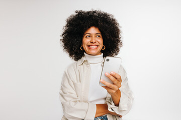 Wall Mural - Thoughtful young woman holding a smartphone in a studio