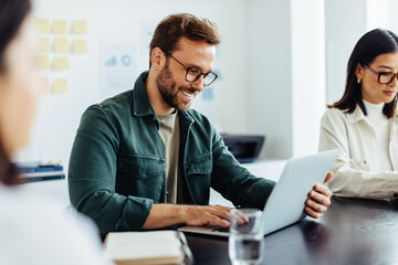 Poster - Designer using a laptop while sitting in a meeting
