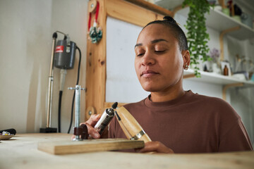 Wall Mural - Close up portrait of black woman creating handmade jewelry in workshop studio