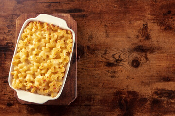 Wall Mural - Macaroni and cheese pasta in a casserole, overhead shot on a rustic background with copy space