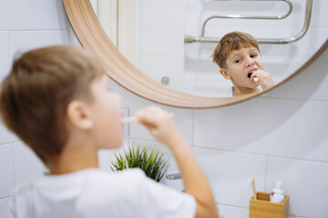 Wall Mural - cute 5 years old boy brushing teeth with bamboo tooth brush in bathroom. Image with selective focus