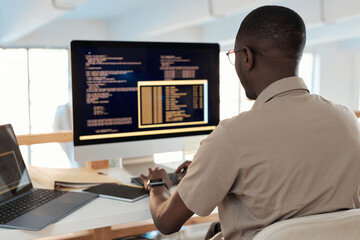Black software developer working on computer, testing code of new application