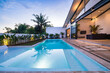 © Roman - Tropical villa view with garden, swimming pool and open living room at sunset