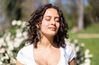 © pablobenii - Young woman with curly hair in the park enjoying the sunshine