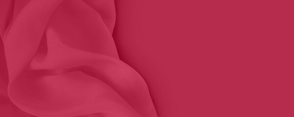 Trendy Color of the Year 2023. Viva magenta. Beautiful abstract silk fabric background. Abstract trendy red toned background with copy space. Flat lay. Banner