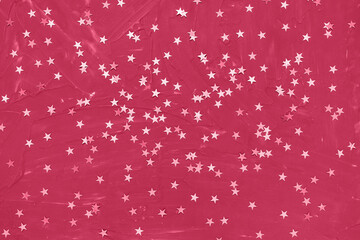 Silver foil confetti stars on dark red background in trendy color of