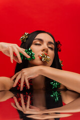 Poster - Young woman with shiny gift bows posing near reflective surface isolated on red