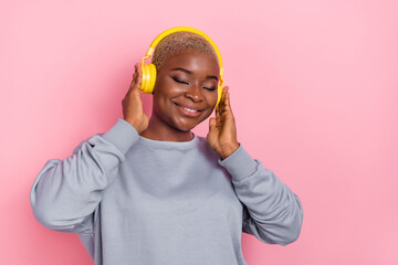 Wall Mural - Portrait of positive adorable girl closed eyes hands touch headphones enjoy new single isolated on pink color background