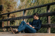 © ADDICTIVE STOCK - Young man sitting on wooden bridge reading book