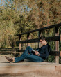 © ADDICTIVE STOCK - Young man sitting on wooden bridge reading book