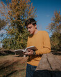 © ADDICTIVE STOCK - Man standing with book on wooden bridge