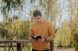© ADDICTIVE STOCK - Man standing with book on wooden bridge