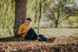 © ADDICTIVE STOCK - Cheerful man sitting under tree reading book