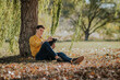 © ADDICTIVE STOCK - Cheerful man sitting under tree reading book