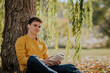 © ADDICTIVE STOCK - Happy man sitting under tree reading book