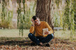 © ADDICTIVE STOCK - Happy man sitting under tree reading book