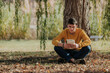 © ADDICTIVE STOCK - Happy man sitting under tree reading book