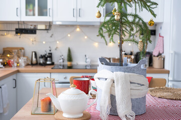 Wall Mural - Festive Christmas decor in white kitchen, festive breakfast, white scandi interior. Araucaria as a Christmas tree is decorated and wrapped in a scarf and felt planters. New Year, mood, cozy home