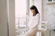 © BullRun - Happy pregnant woman near window