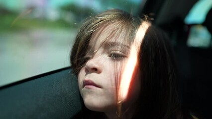 Wall Mural - Sad little girl traveling in car backseat. Bored child closeup face leaning on car window door travels on road. Upset female kid in boredom with depressed emotion