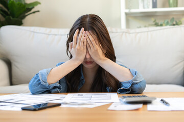 Wall Mural - Financial owe asian woman, female hand in cover face, sitting in stressed and confused by calculate expense from invoice or bill, have no money to pay, mortgage or loan. Debt, bankruptcy or bankrupt.