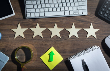 Wooden 5 stars with a business objects on the table. Increase rating