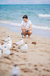 Happy teen girl playing with seagull birds, running and having fun on the beach on a hot summer day. Florida summer holiday vacation