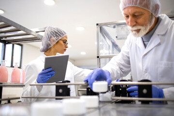 production line workers standing by conveyor machine and controlling manufacturing of cosmetics prod