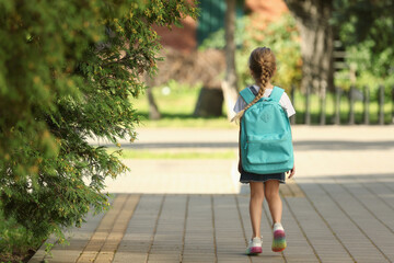 Canvas Print - Little girl with backpack going to school, back view. Space for text